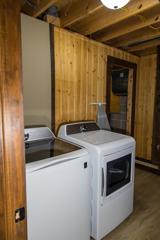 laundry room featuring dark wood-type flooring, wood walls, and washer and clothes dryer