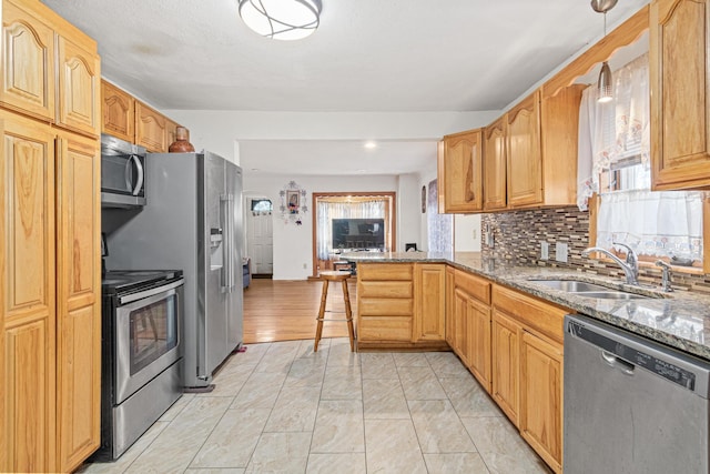 kitchen with sink, a kitchen breakfast bar, appliances with stainless steel finishes, decorative light fixtures, and dark stone countertops