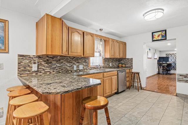 kitchen featuring dishwasher, dark stone counters, kitchen peninsula, and a breakfast bar