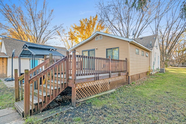 back of house with a deck, central AC unit, and a lawn