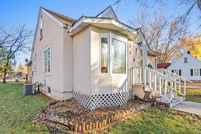 view of side of home featuring central air condition unit and a yard