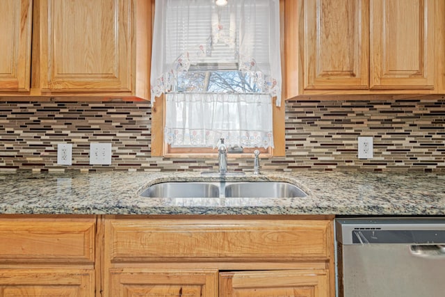 kitchen featuring light stone counters, stainless steel dishwasher, sink, and backsplash