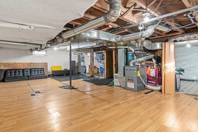 basement with heating unit, hardwood / wood-style flooring, and electric water heater