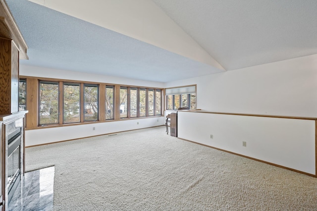 carpeted empty room with vaulted ceiling and a textured ceiling