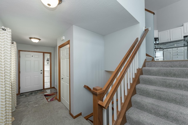 carpeted foyer featuring a textured ceiling