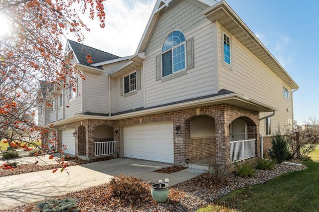 view of front of property featuring a garage, a porch, concrete driveway, and brick siding