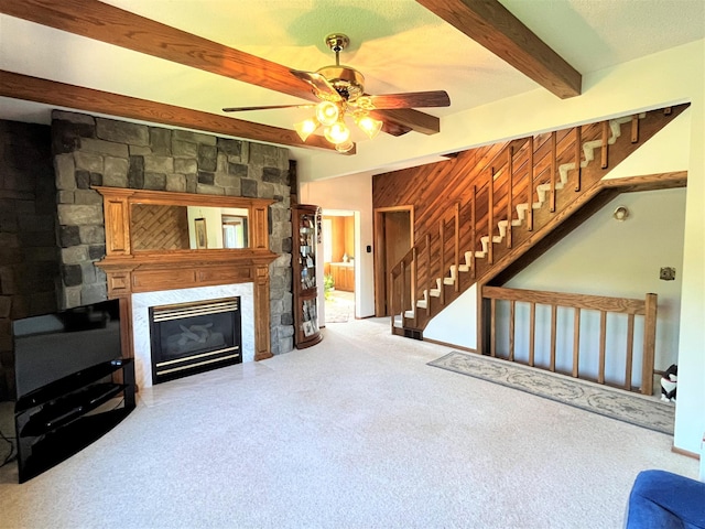 living room featuring carpet flooring, ceiling fan, beam ceiling, and a premium fireplace