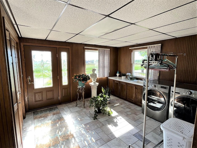 washroom with washer and dryer, wooden walls, cabinets, and sink