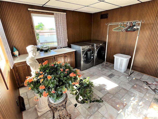 washroom with wood walls, cabinets, a water view, sink, and independent washer and dryer