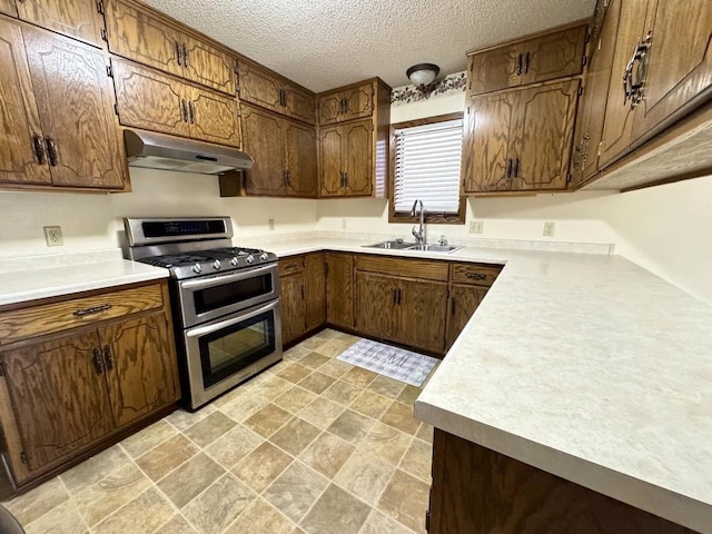 kitchen featuring a textured ceiling, range with two ovens, sink, and exhaust hood