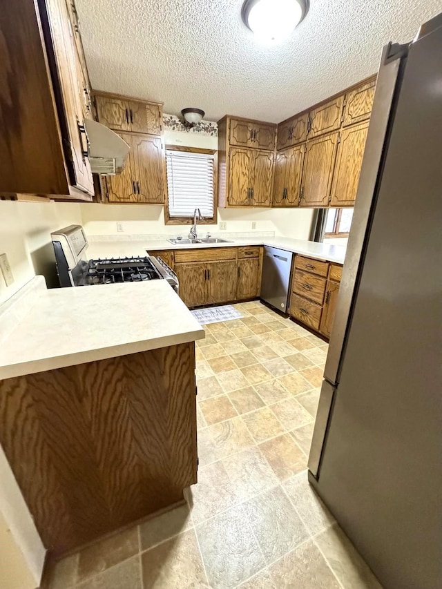 kitchen featuring stainless steel appliances, extractor fan, a textured ceiling, sink, and kitchen peninsula