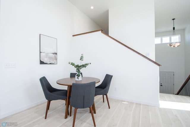 6652 32nd St S, Fargo, ND 58104 - dining area featuring light wood-style flooring, stairs, a chandelier, a high ceiling, and baseboards