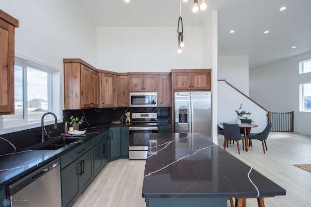 6652 32nd St S, Fargo, ND 58104 - kitchen featuring stainless steel appliances, a sink, a towering ceiling, light wood finished floors, and a center island