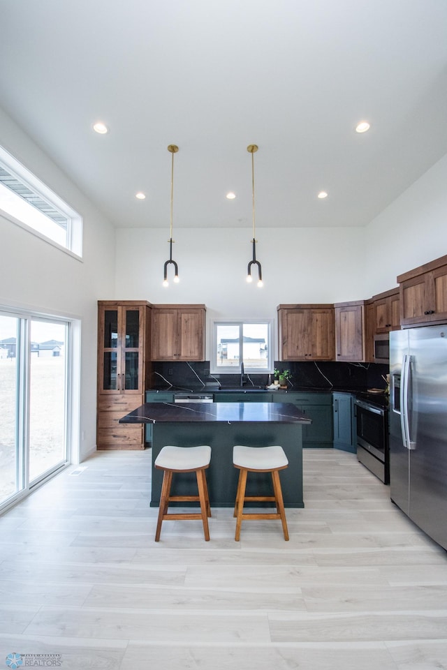 6652 32nd St S, Fargo, ND 58104 - kitchen featuring stainless steel appliances, dark countertops, a center island, decorative backsplash, and a towering ceiling