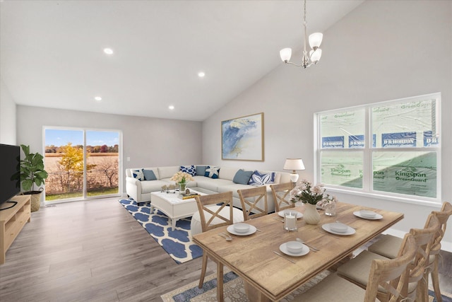 dining room with high vaulted ceiling, wood-type flooring, and an inviting chandelier