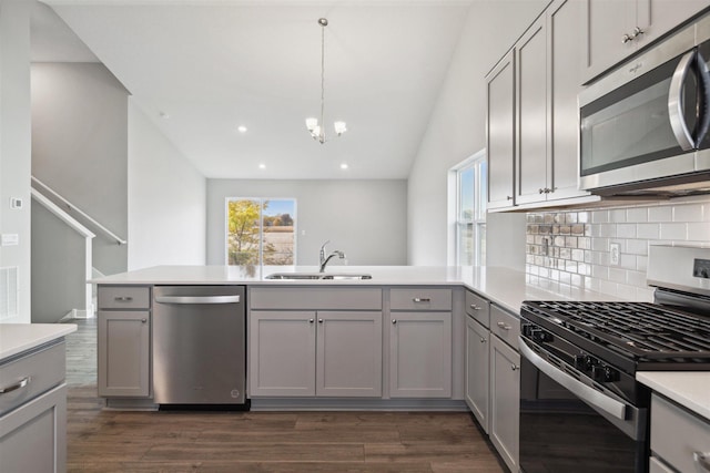 kitchen with gray cabinetry, appliances with stainless steel finishes, sink, dark wood-type flooring, and kitchen peninsula