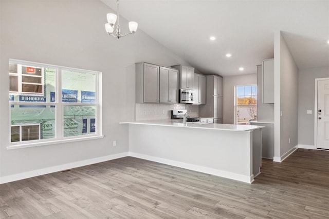 kitchen with pendant lighting, kitchen peninsula, stainless steel appliances, and a healthy amount of sunlight