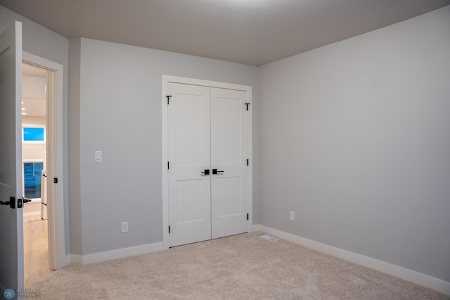 unfurnished bedroom with a closet and light colored carpet