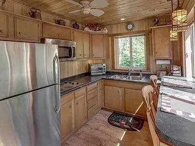 kitchen featuring sink, appliances with stainless steel finishes, ceiling fan, wood ceiling, and light hardwood / wood-style flooring