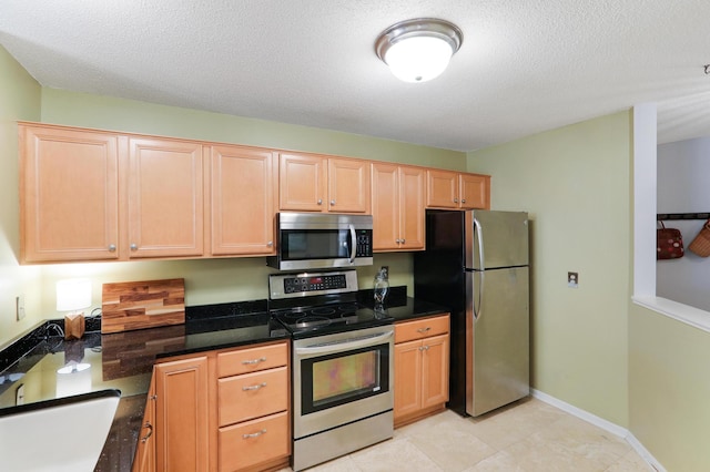 kitchen featuring light brown cabinets, stainless steel appliances, and a textured ceiling