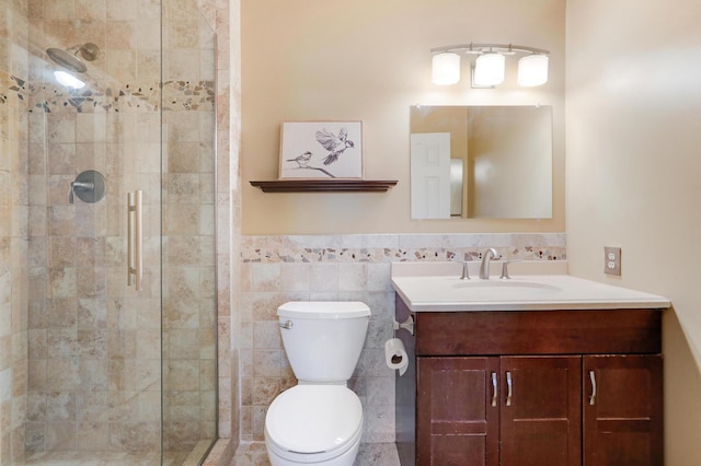 bathroom featuring a shower with shower door, vanity, toilet, and tile walls