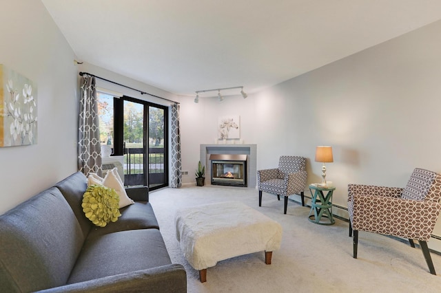 living room with a glass covered fireplace, rail lighting, and light colored carpet