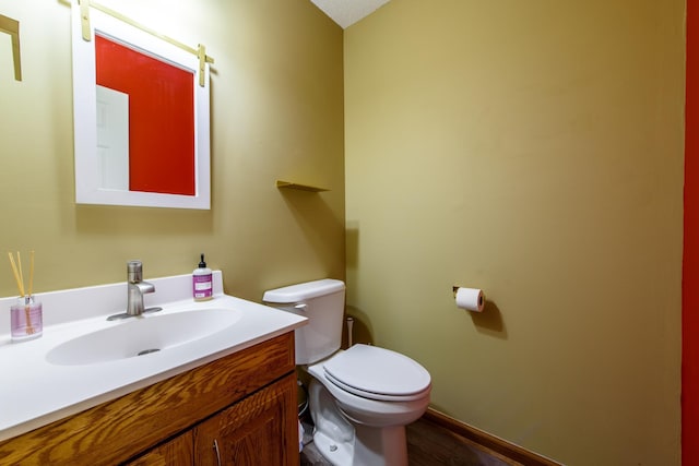 bathroom with toilet, vanity, and wood-type flooring