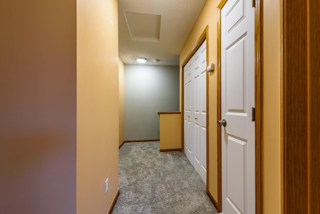 corridor featuring a textured ceiling and light carpet