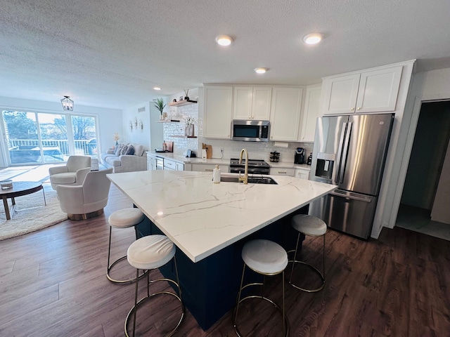 kitchen with light stone countertops, white cabinetry, sink, dark hardwood / wood-style flooring, and appliances with stainless steel finishes