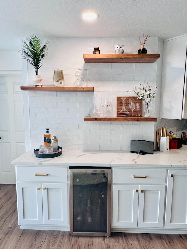 bar featuring light hardwood / wood-style floors, light stone counters, white cabinetry, and wine cooler