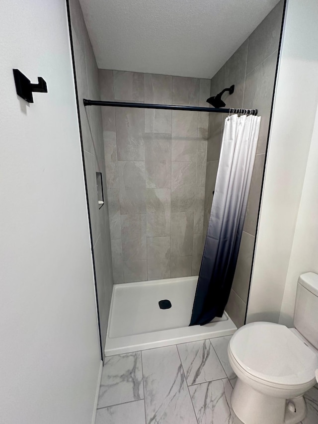 bathroom featuring curtained shower, toilet, and a textured ceiling