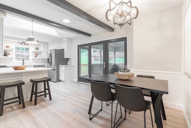 dining room featuring light wood-type flooring, a chandelier, sink, and beam ceiling