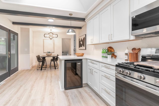 kitchen with light hardwood / wood-style floors, white cabinets, pendant lighting, appliances with stainless steel finishes, and wine cooler