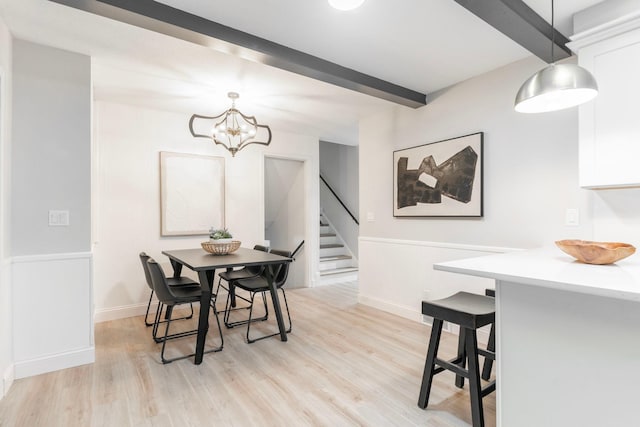 dining area featuring a chandelier, light hardwood / wood-style floors, and beam ceiling