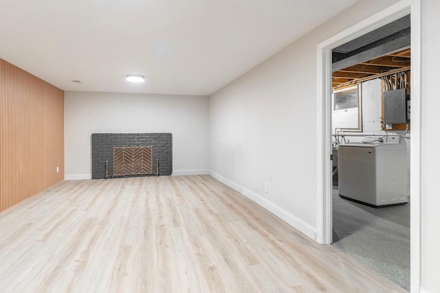 interior space featuring a fireplace, washing machine and dryer, light wood-type flooring, and electric panel