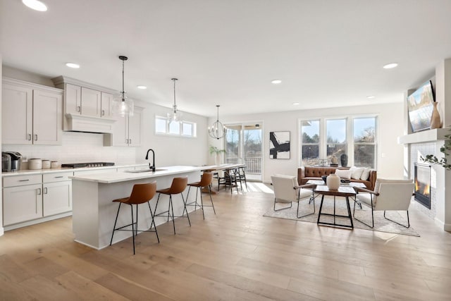 kitchen featuring a kitchen island with sink, light hardwood / wood-style flooring, and white cabinets