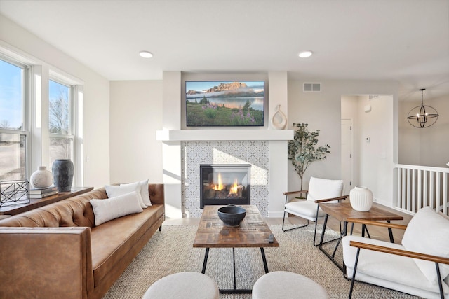 living room with a notable chandelier, a fireplace, and light hardwood / wood-style flooring