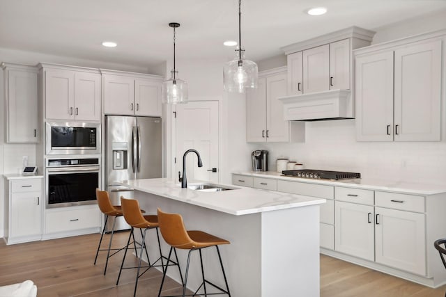 kitchen featuring white cabinets, sink, stainless steel appliances, and a center island with sink