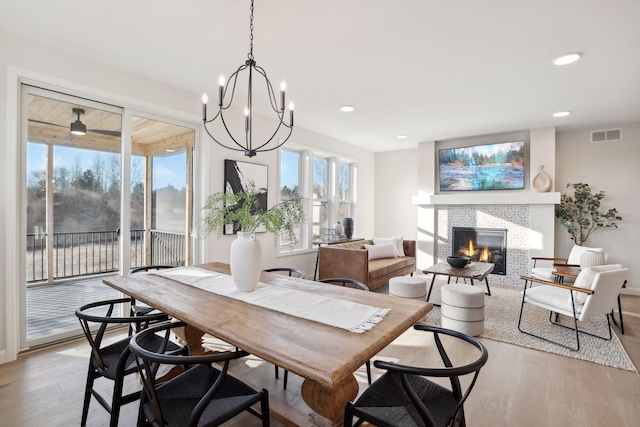 dining area featuring a fireplace, light wood-type flooring, and a chandelier