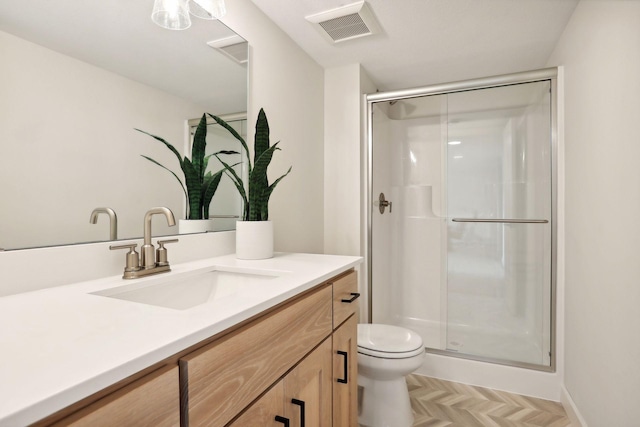 bathroom with parquet flooring, vanity, toilet, and a shower with door