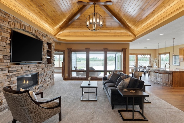 living room featuring light hardwood / wood-style floors, a chandelier, wood ceiling, a stone fireplace, and vaulted ceiling with beams