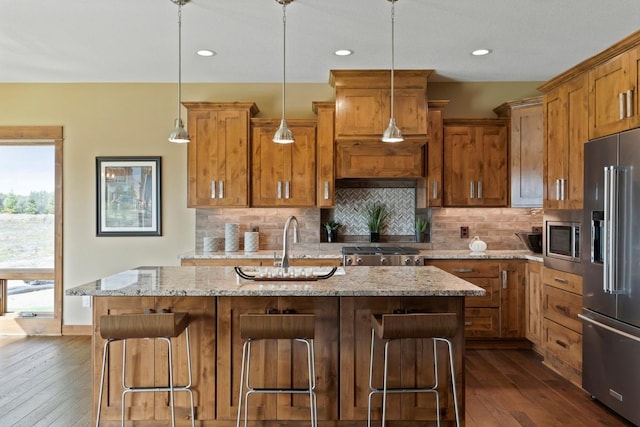 kitchen with a kitchen breakfast bar, appliances with stainless steel finishes, and a center island with sink