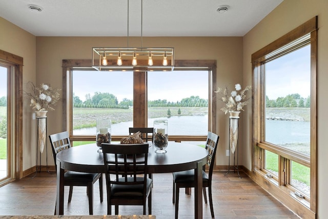 dining area featuring hardwood / wood-style floors, a water view, and a textured ceiling