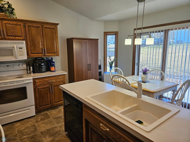 kitchen featuring sink, white appliances, a textured ceiling, and pendant lighting