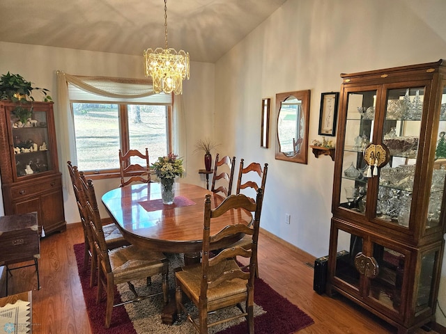 dining area with dark hardwood / wood-style flooring and an inviting chandelier