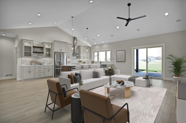 living room featuring ceiling fan, light hardwood / wood-style floors, sink, and high vaulted ceiling