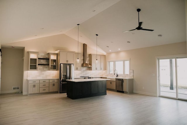 kitchen featuring pendant lighting, light hardwood / wood-style flooring, wall chimney exhaust hood, a kitchen island, and stainless steel appliances