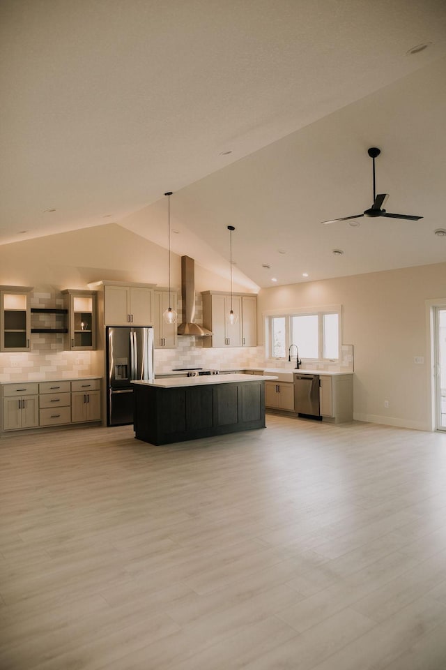 kitchen with wall chimney exhaust hood, stainless steel appliances, a kitchen island, hanging light fixtures, and lofted ceiling