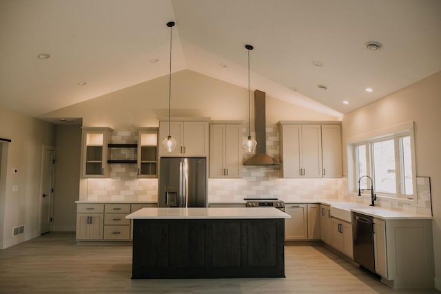 kitchen with a center island, sink, wall chimney exhaust hood, decorative light fixtures, and stainless steel appliances