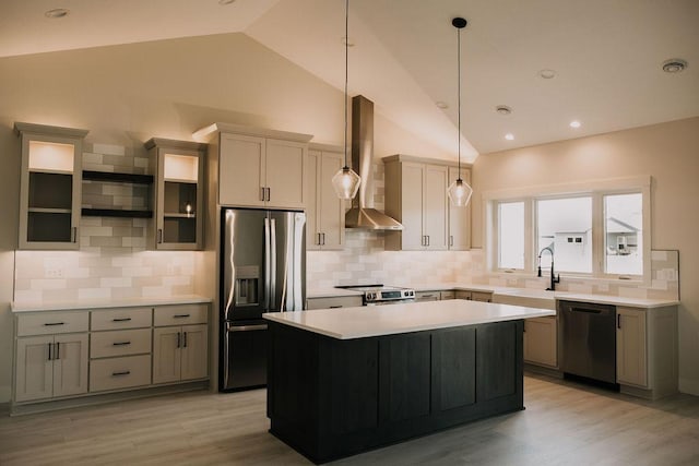 kitchen with a center island, wall chimney range hood, pendant lighting, decorative backsplash, and appliances with stainless steel finishes